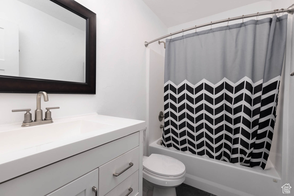 Bathroom featuring vanity, shower / bath combo with shower curtain, and toilet