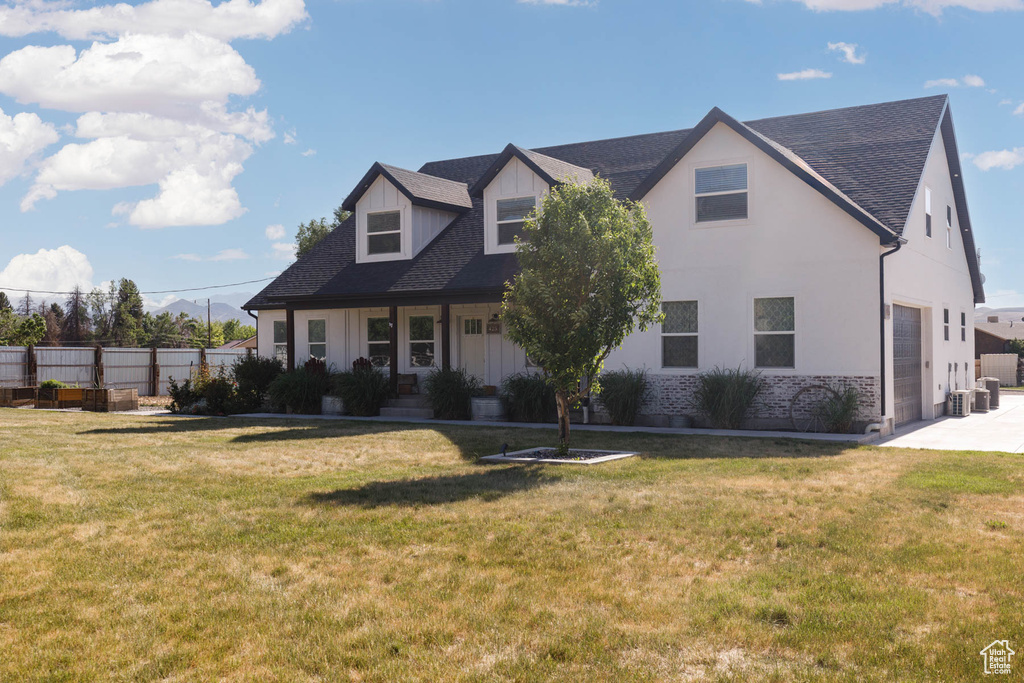 Cape cod home featuring a garage, board and batten siding, roof with shingles, driveway, and central air condition unit