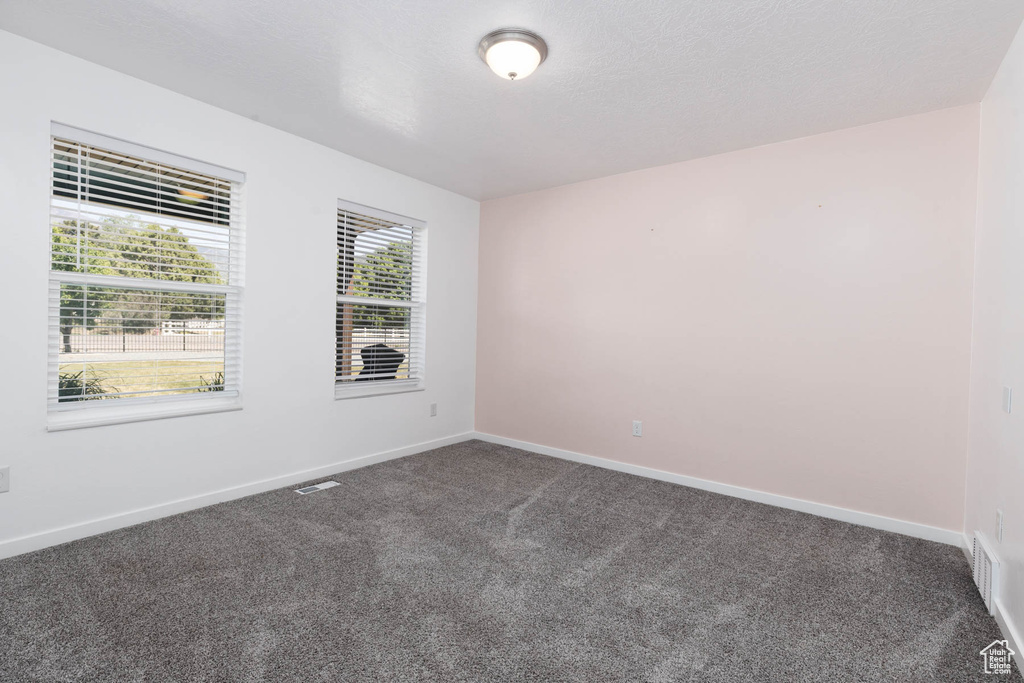 Empty room featuring dark colored carpet and baseboards