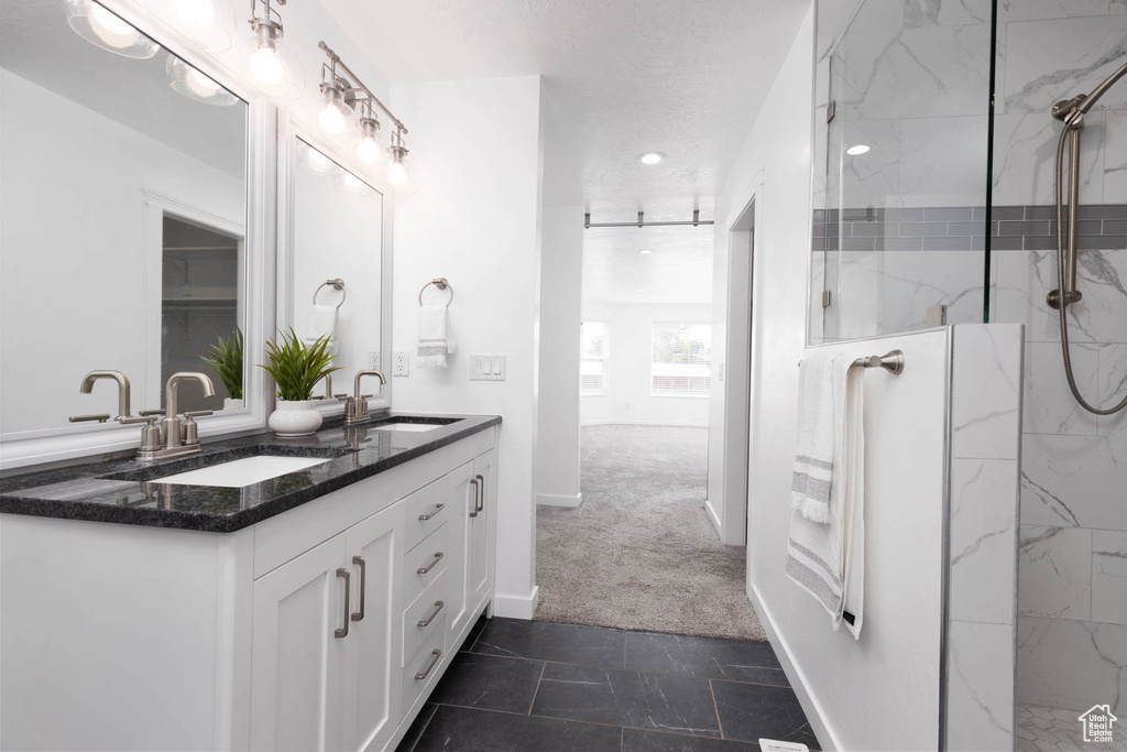 Bathroom featuring double vanity, a marble finish shower, and recessed lighting
