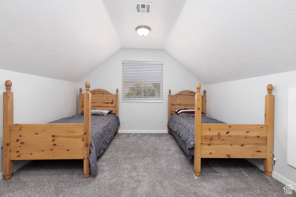 Bedroom with carpet floors, vaulted ceiling, a textured ceiling, and baseboards