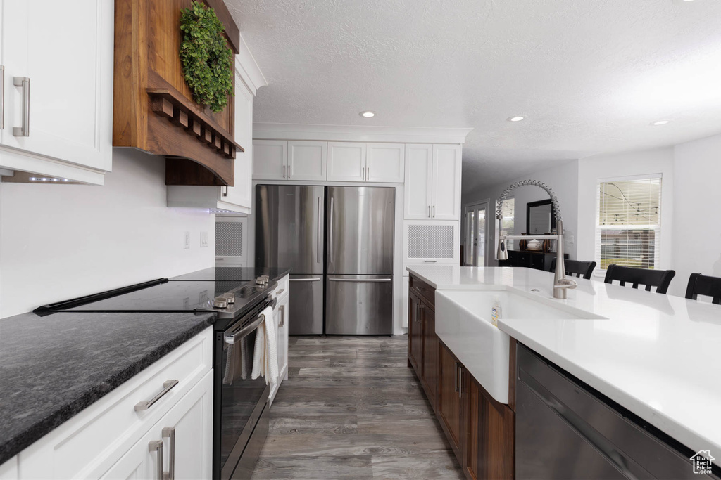 Kitchen featuring appliances with stainless steel finishes, a sink, white cabinetry, dark wood-style flooring, and recessed lighting