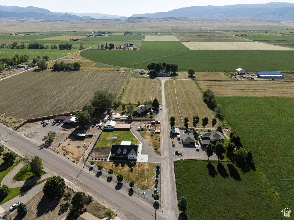 Aerial overview of property's location with rural landscape, large plots for crops, and a mountainous background