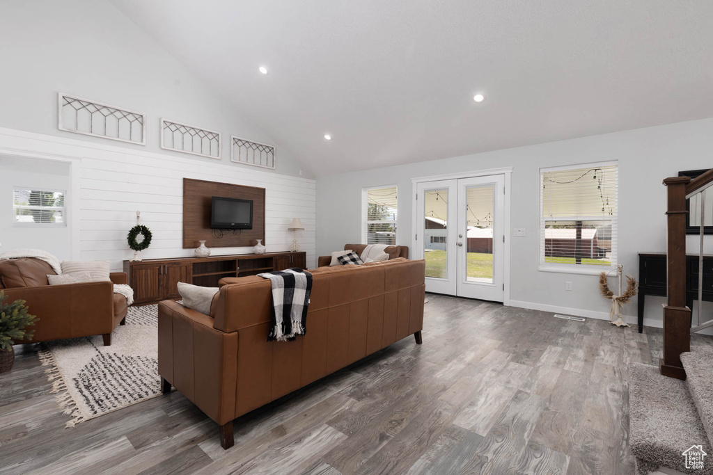 Living room featuring wood finished floors, healthy amount of natural light, recessed lighting, high vaulted ceiling, and baseboards
