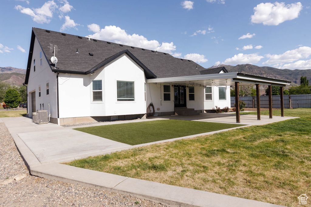 Rear view of house featuring a mountain view, roof with shingles, and a patio