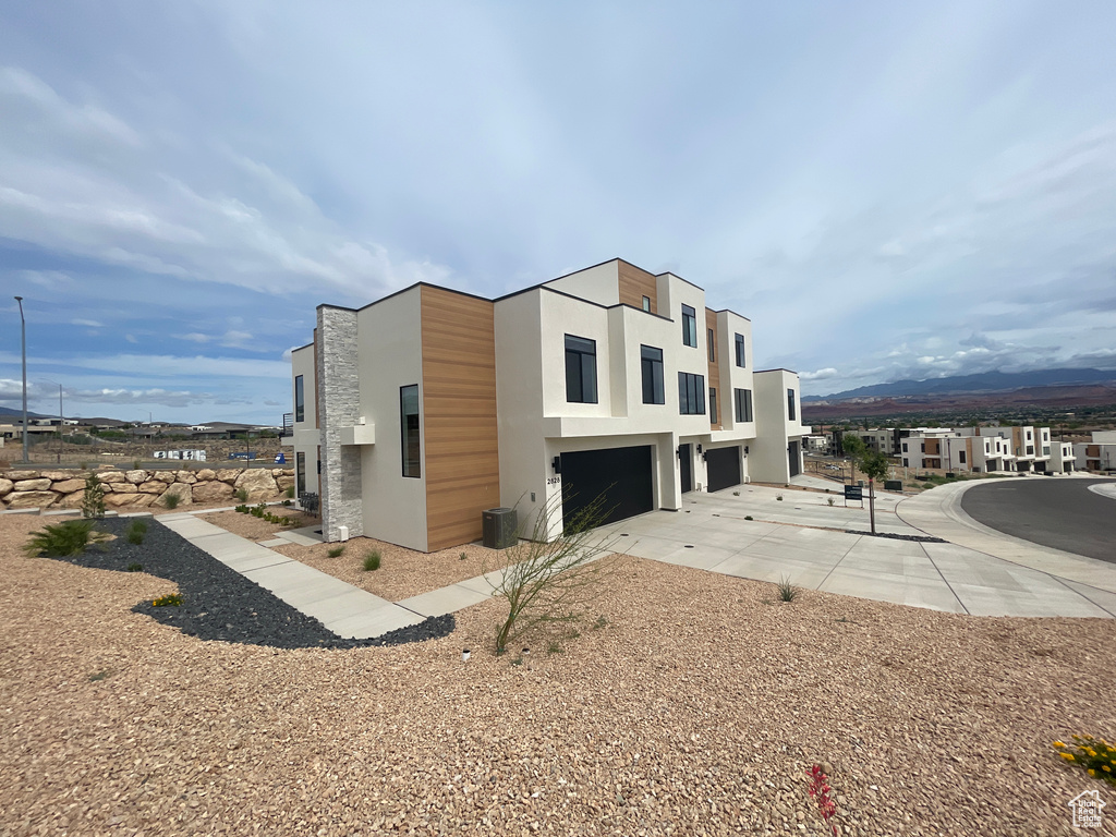 View of property exterior featuring an attached garage, stucco siding, and a mountain view