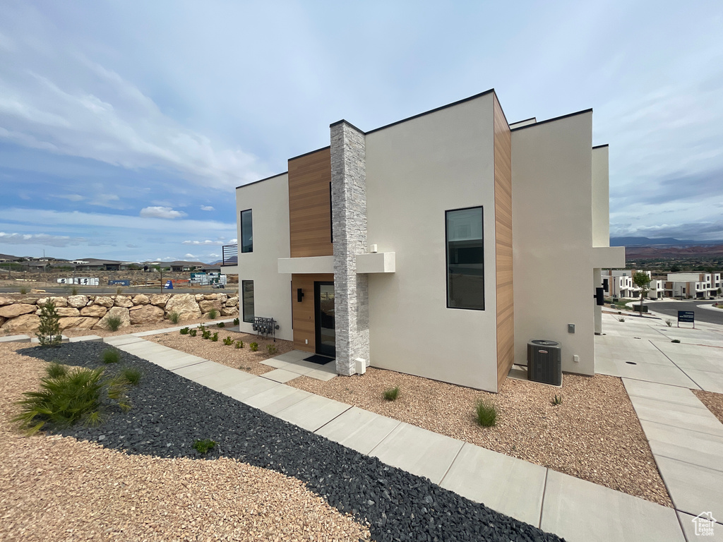 View of side of property with stucco siding and cooling unit