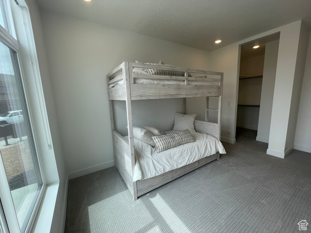 Carpeted bedroom featuring baseboards, recessed lighting, and a walk in closet