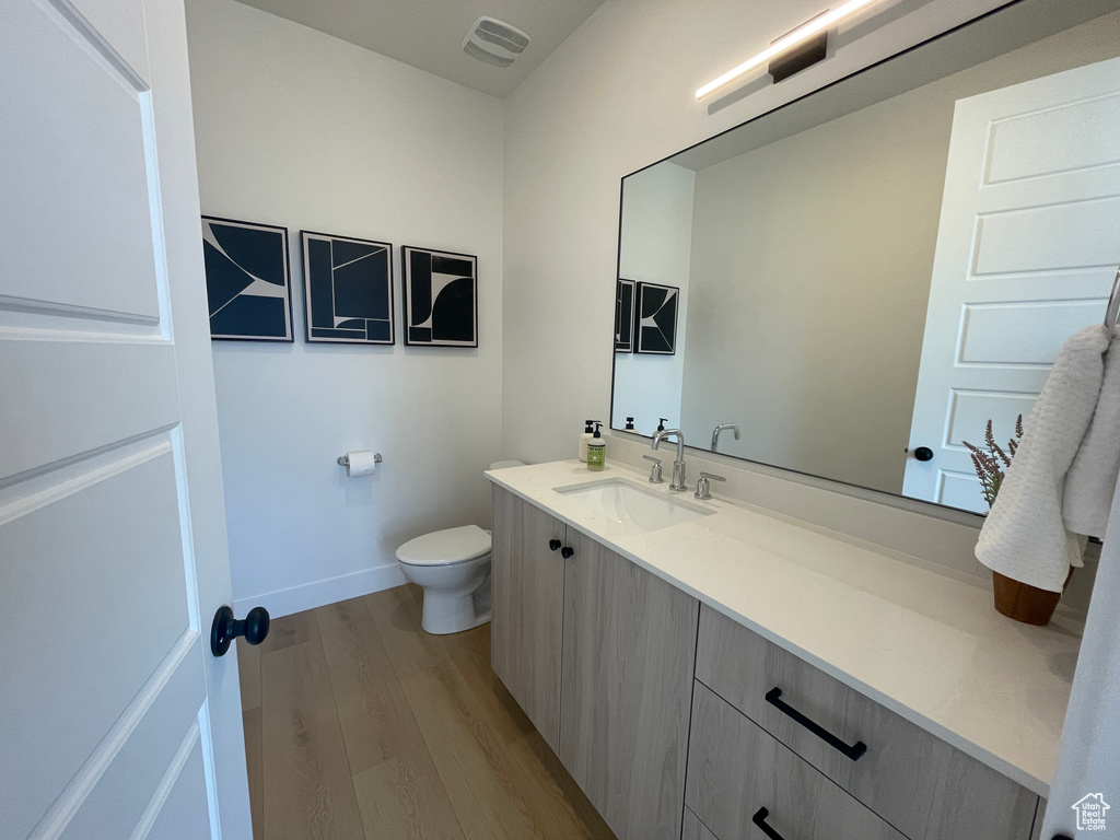 Bathroom with wood finished floors, vanity, toilet, and baseboards