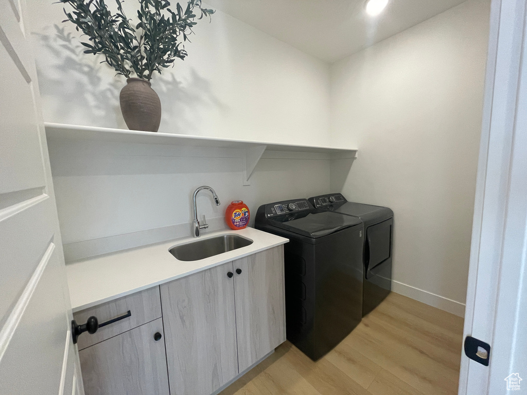 Laundry area with cabinet space, separate washer and dryer, light wood-type flooring, baseboards, and recessed lighting
