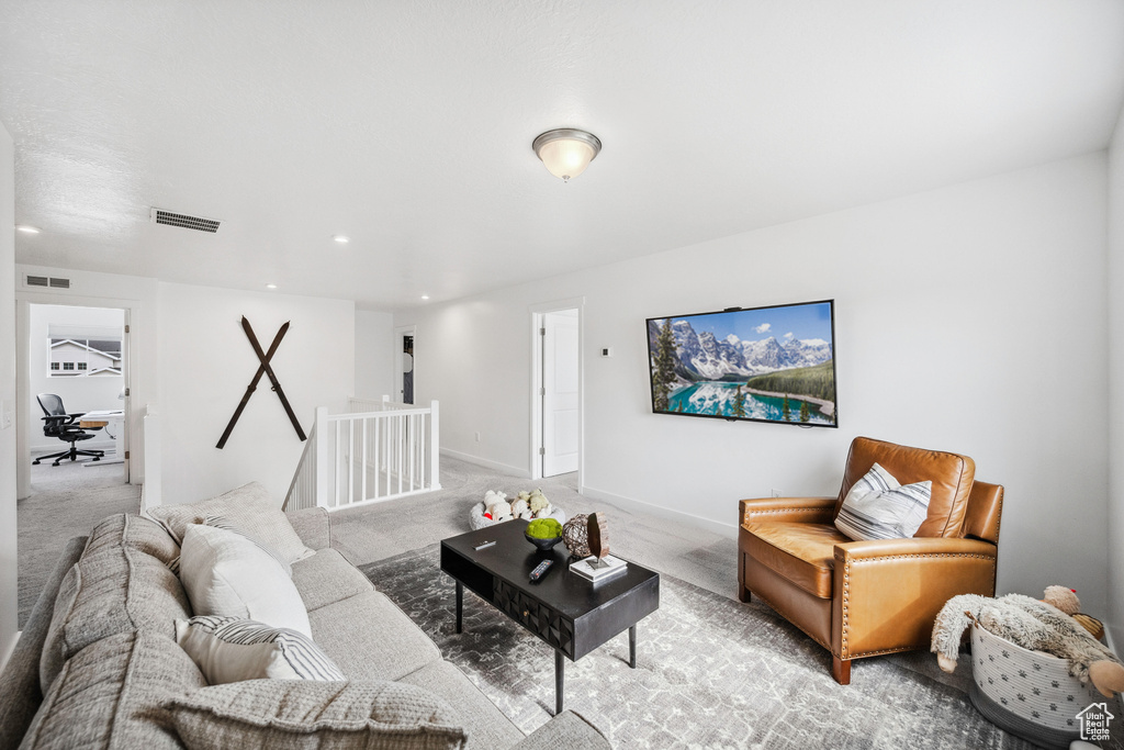 Living area with light colored carpet and recessed lighting