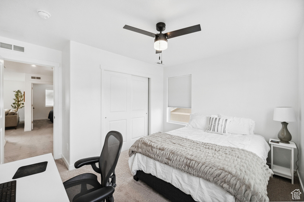 Bedroom with carpet, a closet, a desk, a ceiling fan, and baseboards