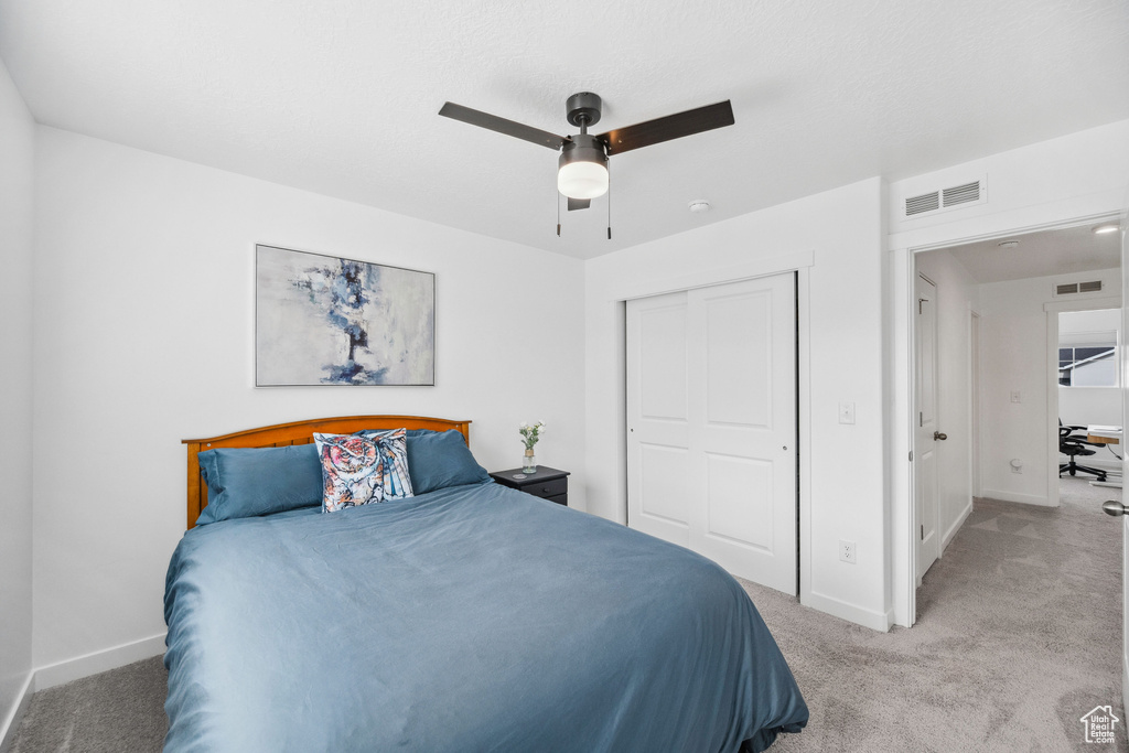 Bedroom with light carpet, baseboards, a closet, and ceiling fan