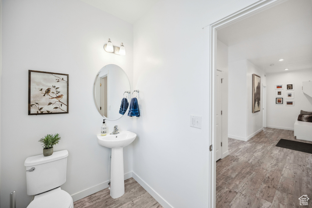 Bathroom featuring wood finished floors, toilet, a sink, recessed lighting, and baseboards