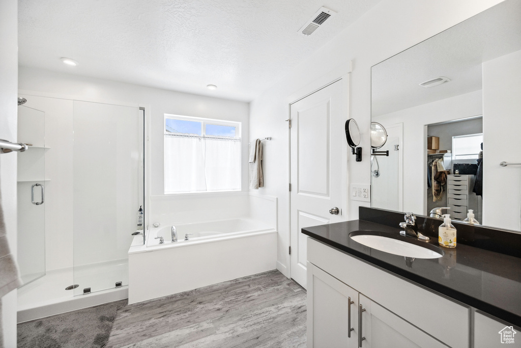 Full bath featuring a stall shower, wood finished floors, a bath, a walk in closet, and vanity
