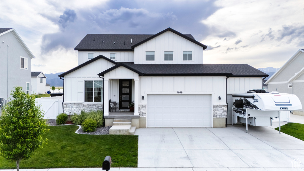Modern farmhouse style home featuring board and batten siding, concrete driveway, stone siding, and roof with shingles