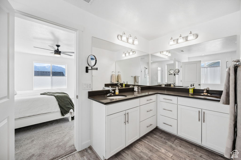 Ensuite bathroom featuring double vanity, wood finished floors, and ceiling fan