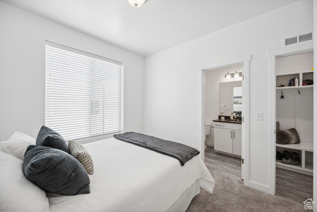 Bedroom featuring ensuite bathroom, baseboards, and light carpet