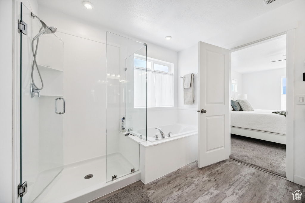 Ensuite bathroom with a shower stall, a bath, and wood finished floors