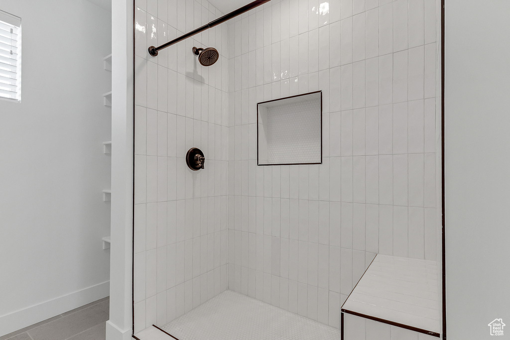 Full bathroom with a tile shower, baseboards, and tile patterned floors