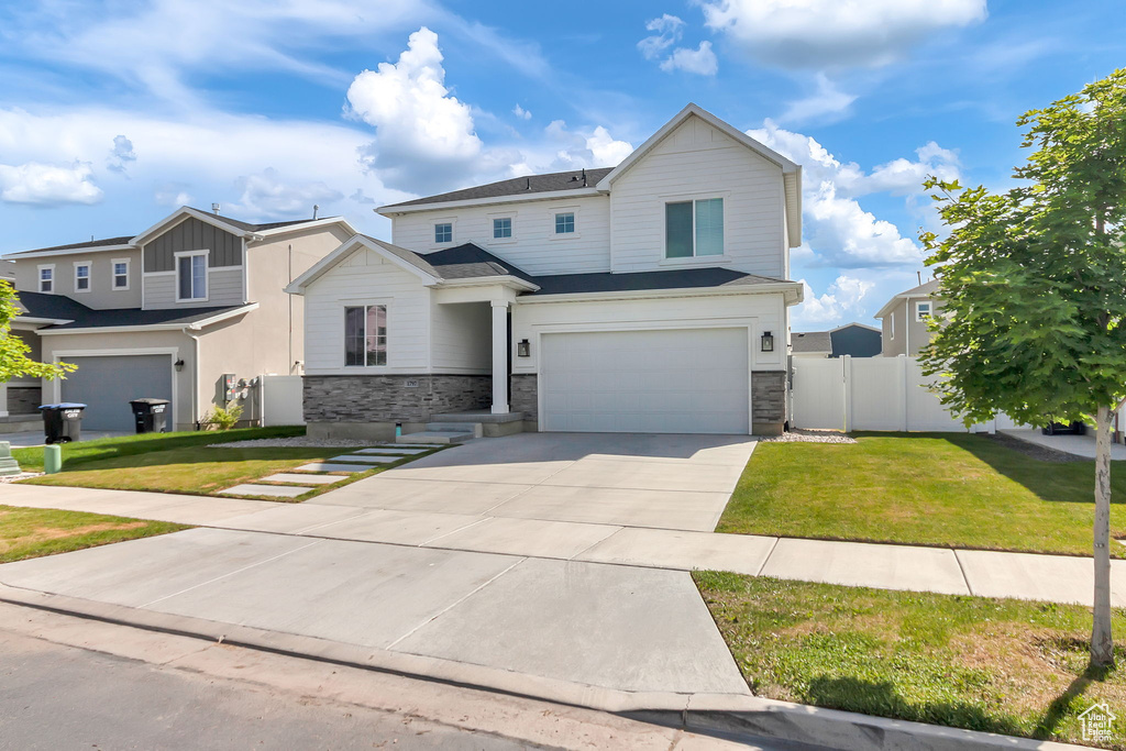 View of front of home featuring an attached garage, stone siding, and driveway