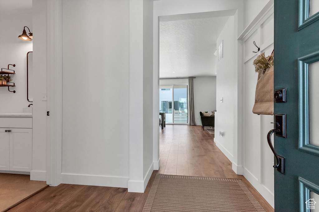 Hall featuring wood finished floors, baseboards, and a sink