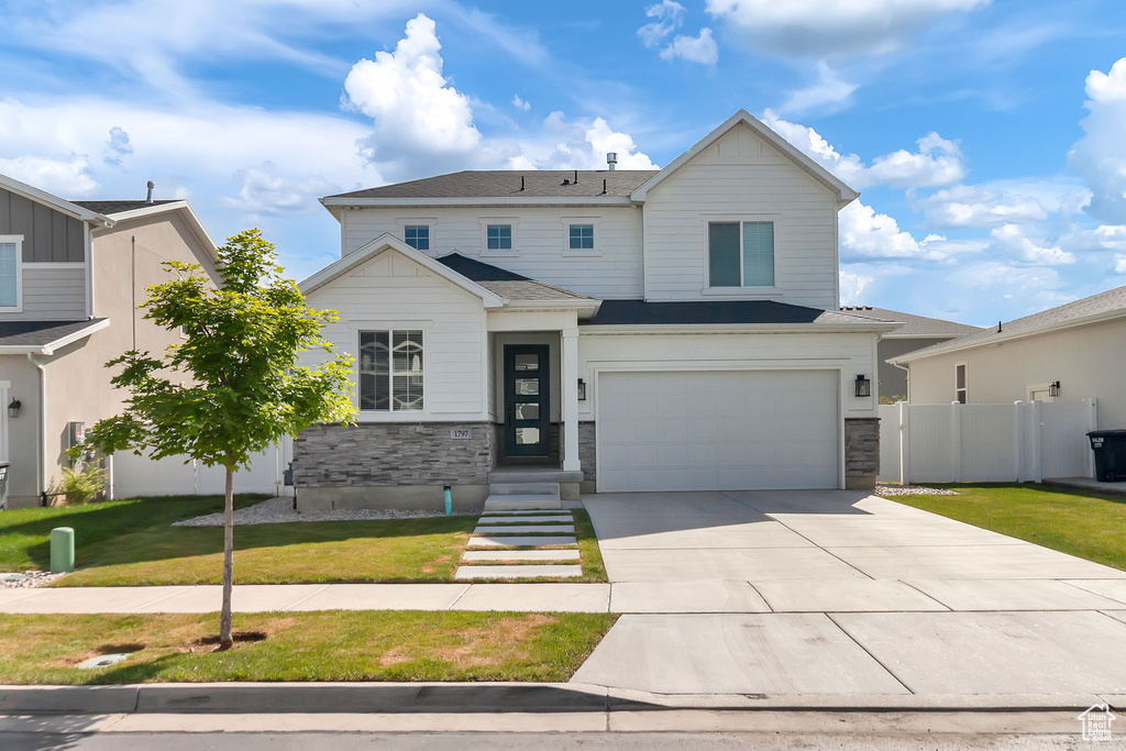 View of front of property featuring stone siding, a garage, and driveway