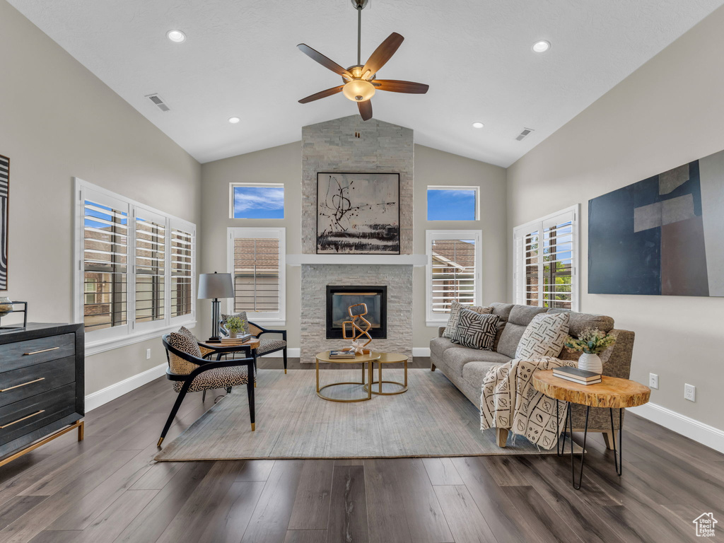 Living room with a ceiling fan, baseboards, high vaulted ceiling, dark wood-style flooring, and a fireplace