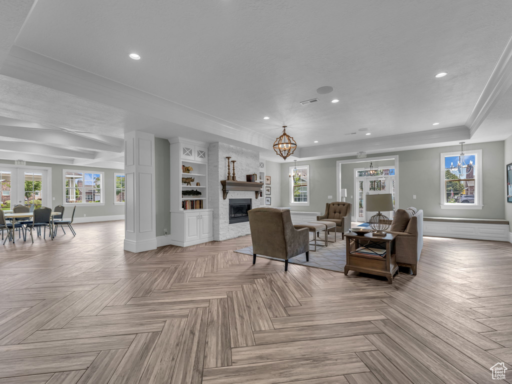 Living room with a chandelier, a fireplace, healthy amount of natural light, recessed lighting, and ornamental molding