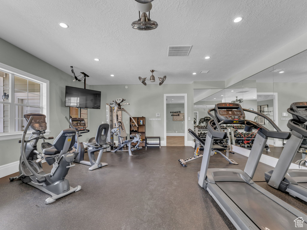 Exercise room featuring a textured ceiling, recessed lighting, and baseboards