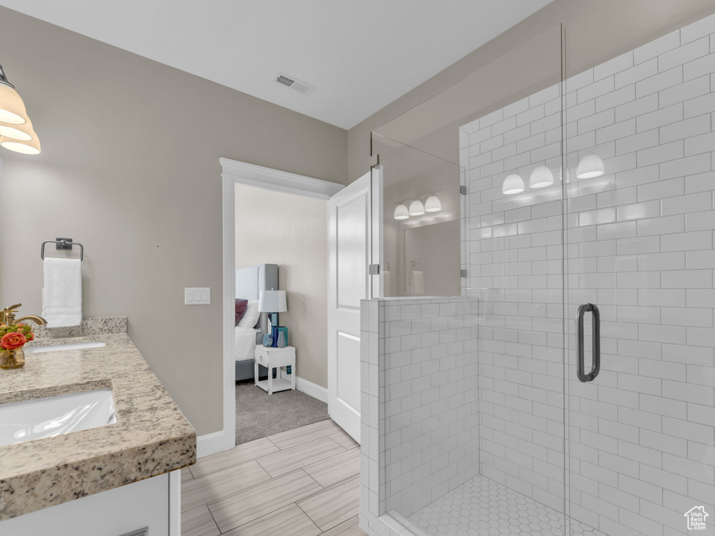 Bathroom featuring ensuite bathroom, double vanity, a shower stall, and baseboards