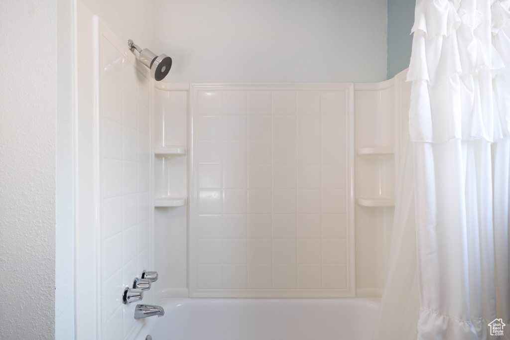 Bathroom view of shower / bathtub combination with curtain