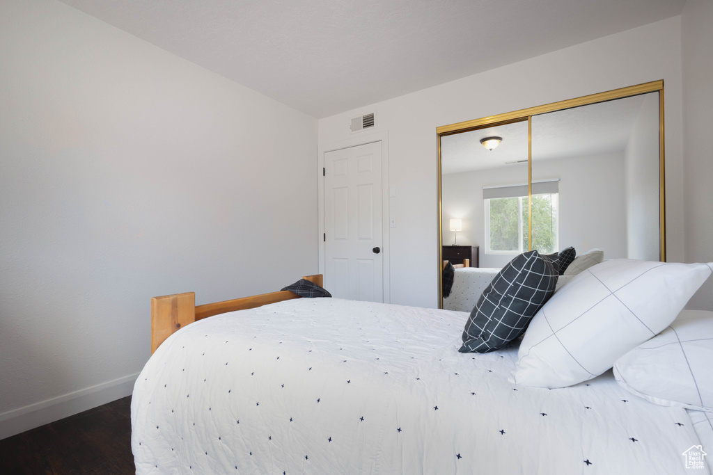 Bedroom featuring wood finished floors, baseboards, and a closet