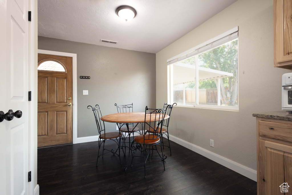 Dining area with dark wood-style flooring and baseboards