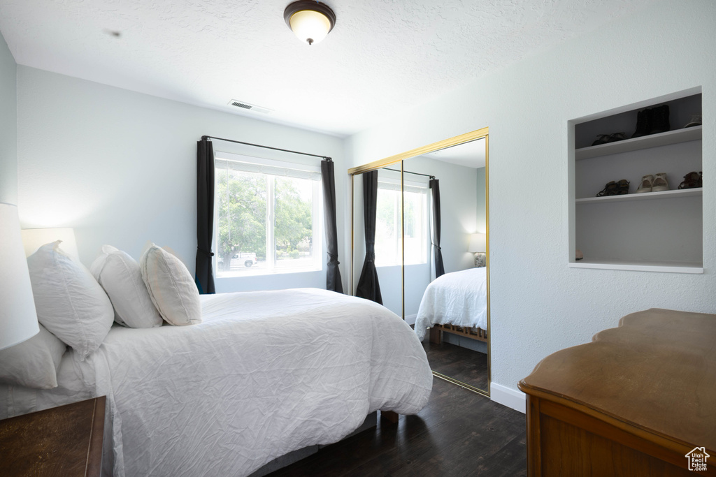 Bedroom featuring dark wood-style flooring, a closet, and baseboards