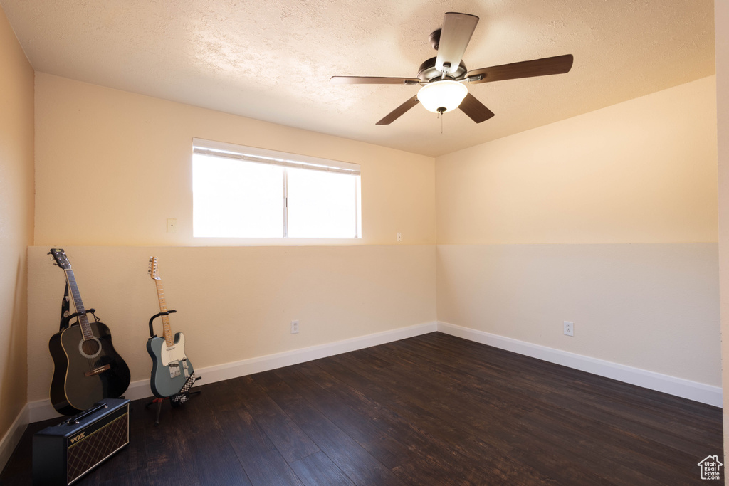 Spare room with dark wood-style flooring, baseboards, ceiling fan, and a textured ceiling