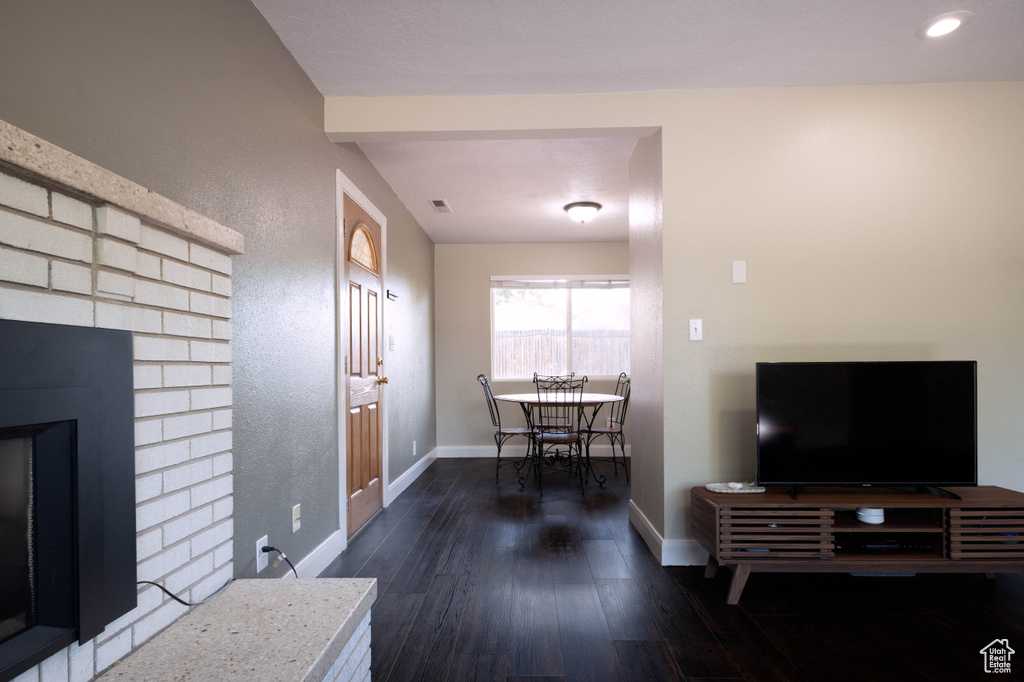 Living room with wood finished floors, baseboards, a fireplace, and recessed lighting