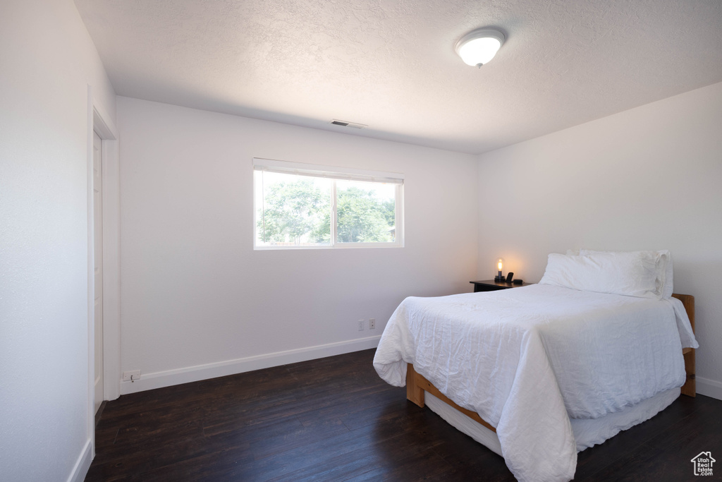 Bedroom featuring baseboards, dark wood finished floors, and a textured ceiling