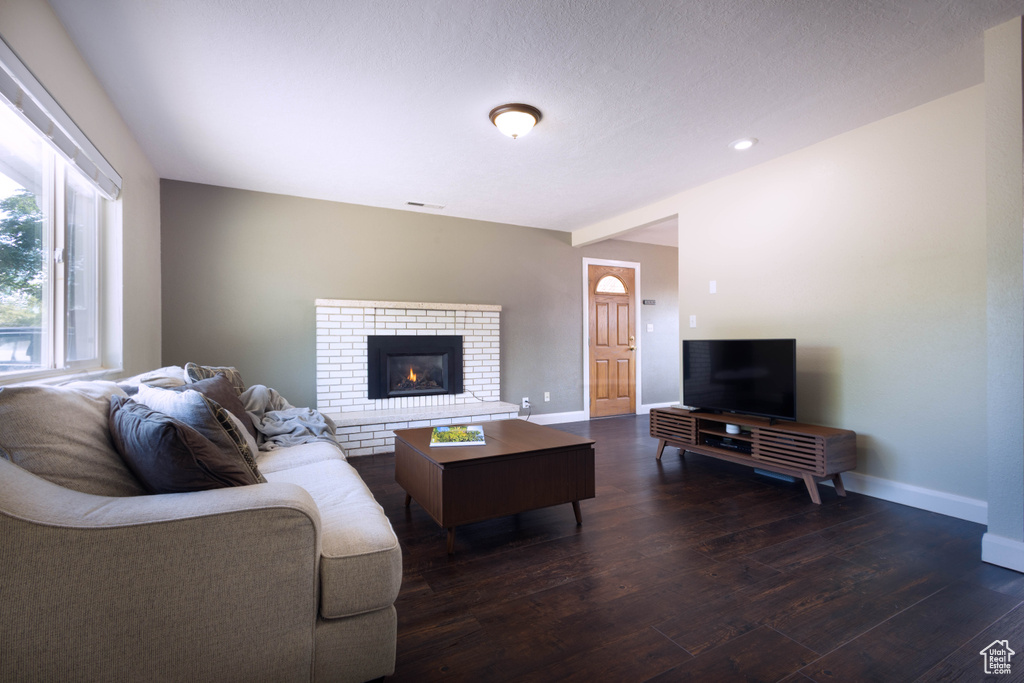 Living area featuring dark wood-style flooring, baseboards, and a fireplace