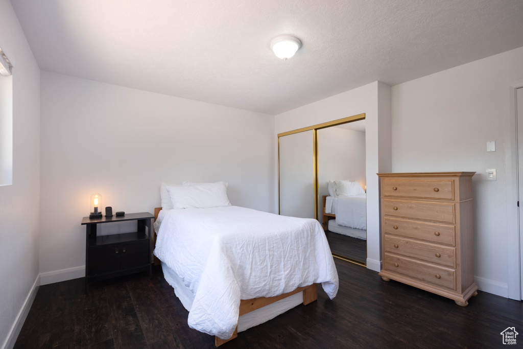 Bedroom with a closet, wood finished floors, and baseboards