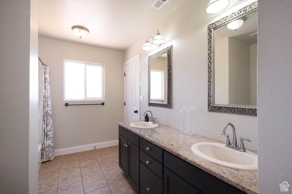 Full bath featuring double vanity, tile patterned flooring, and baseboards