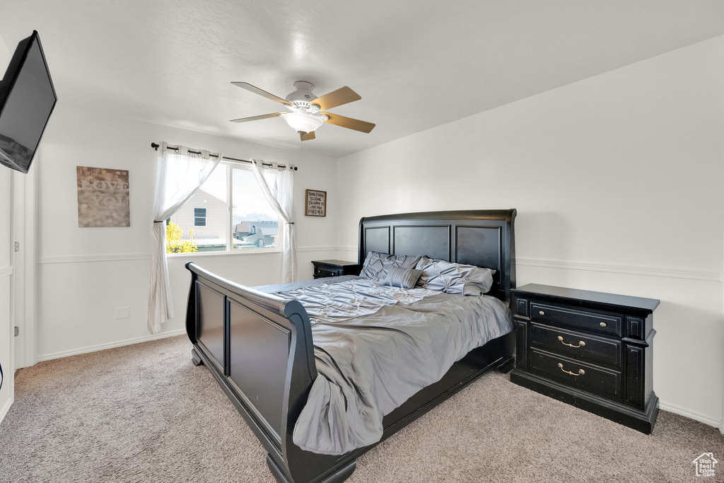 Carpeted bedroom featuring ceiling fan and baseboards