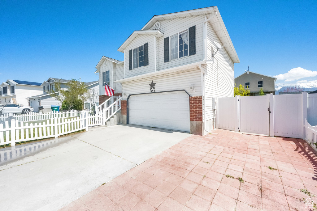View of front of property featuring a gate, an attached garage, and driveway