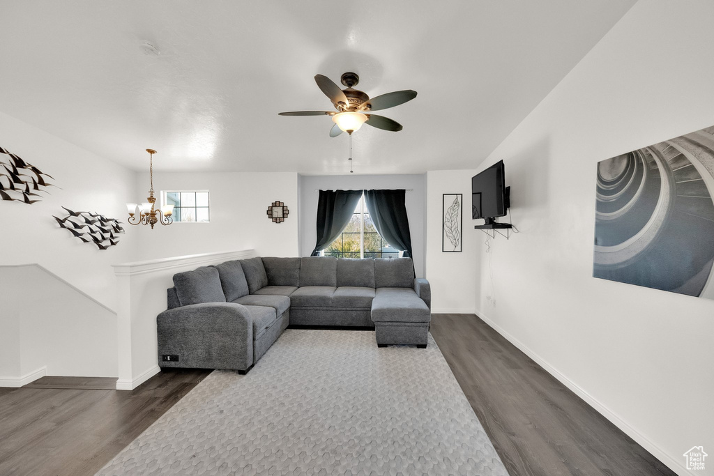 Living room with dark wood finished floors, plenty of natural light, a chandelier, and ceiling fan