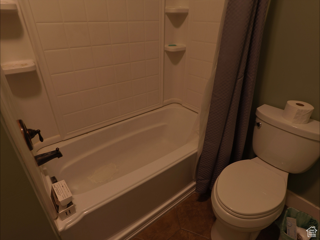 Full bath featuring toilet, tile patterned floors, and shower / bath combo with shower curtain