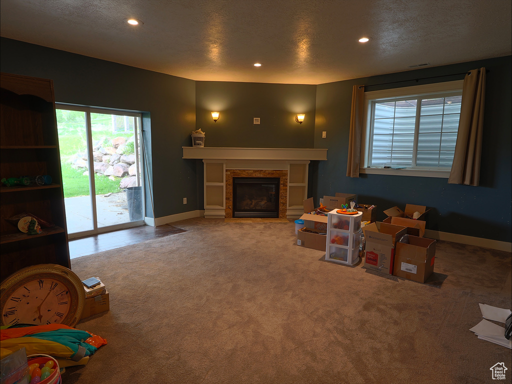 Living room featuring carpet, healthy amount of natural light, a glass covered fireplace, recessed lighting, and baseboards