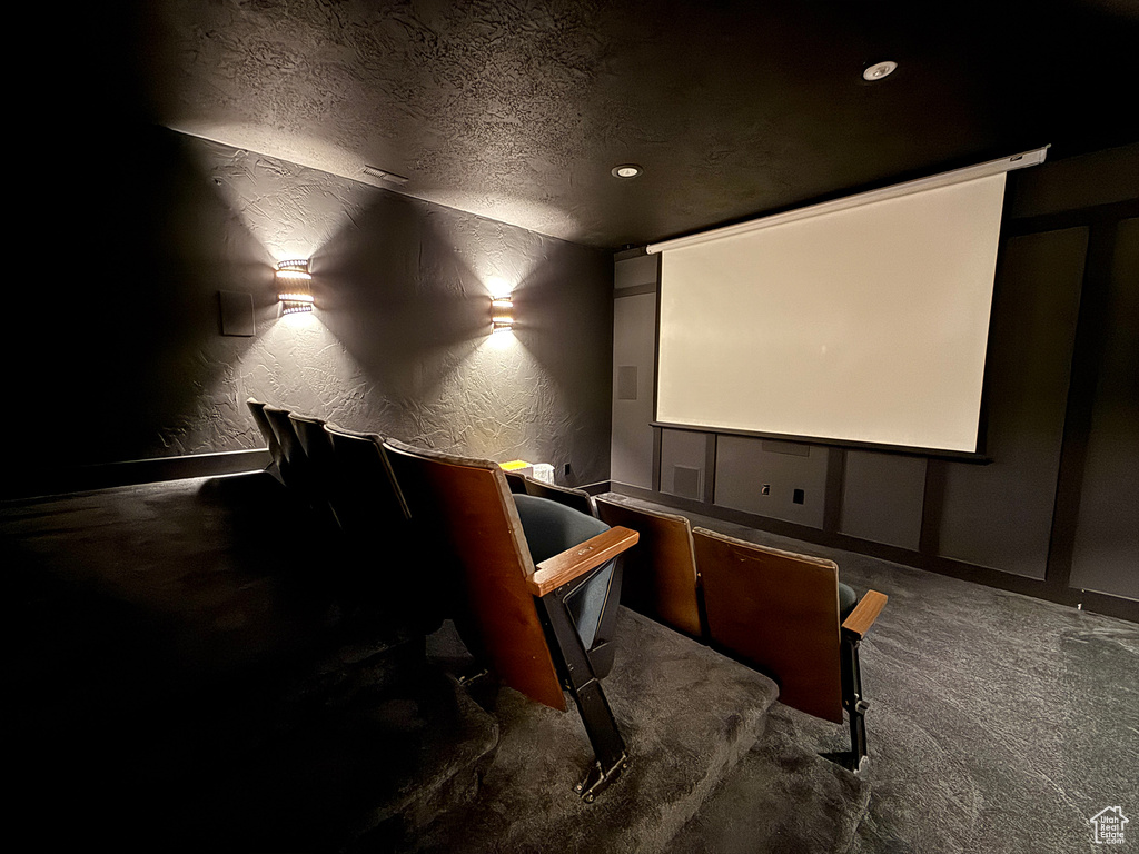 Carpeted home theater room featuring a textured wall and a textured ceiling
