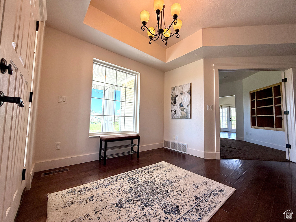 Entryway featuring dark wood-style flooring, a chandelier, and a tray ceiling