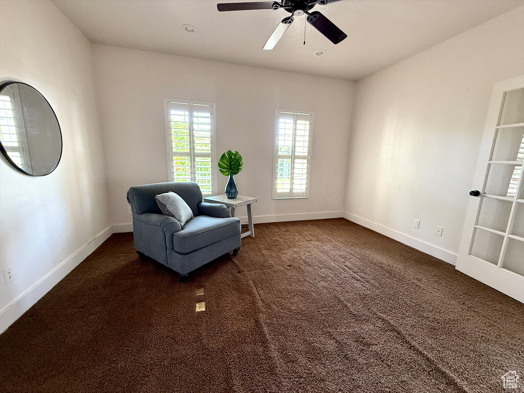 Living area with ceiling fan and dark carpet