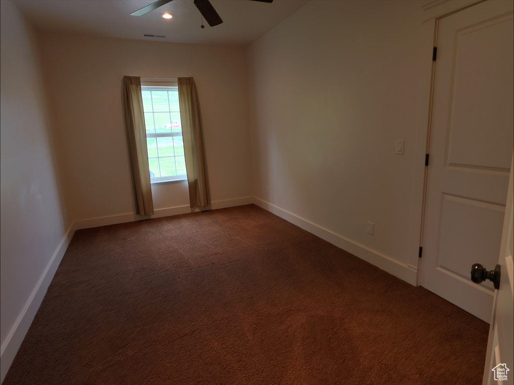 Empty room featuring ceiling fan, dark carpet, baseboards, and recessed lighting